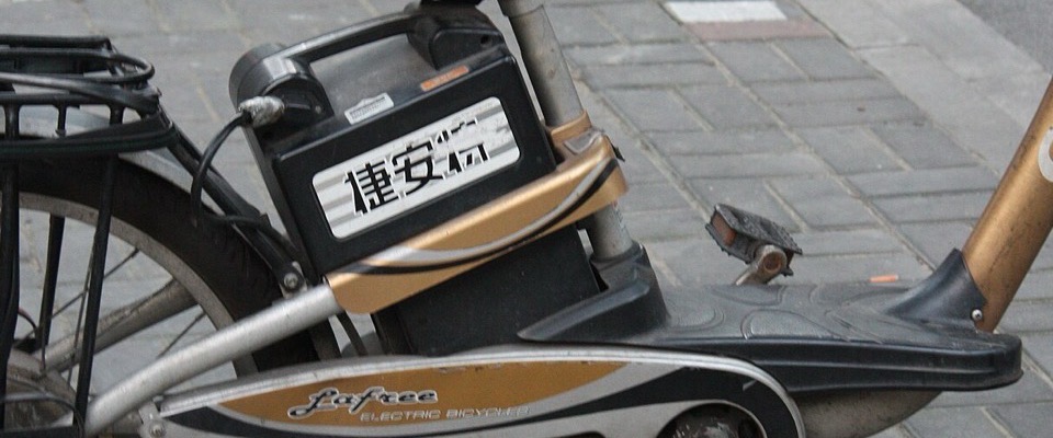 A Chinese-made e-bike with its rear-mounted lithium battery pack, parked on a pavement